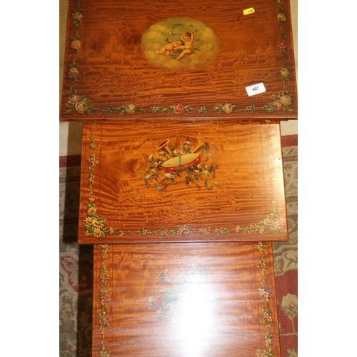 487 - A late 19th century satinwood nest of three tables, tops painted central cherub panel and floral bor... 