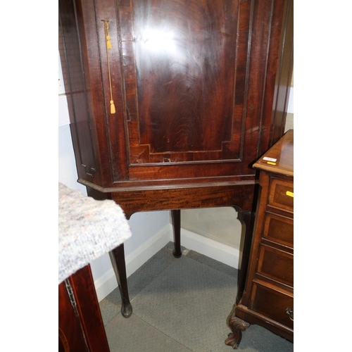 555 - A George III crossbanded mahogany corner cupboard on stand with panel door enclosing shaped front sh... 