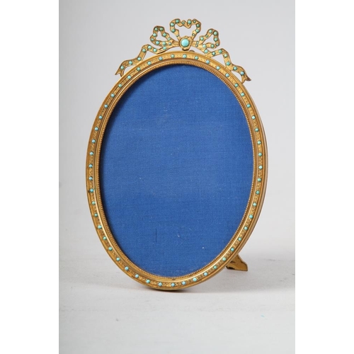 181 - A 19th century gilt metal oval shaped picture frame, inset turquoise with ribbon finial, supplied by... 