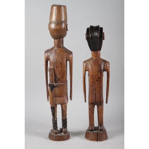 205 - Two East African carved hardwood figures, he in military uniform, she naked, largest 27 1/2