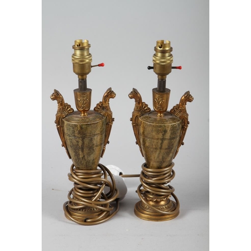 299 - A pair of gilt metal and anodised two-handled vase shaped table lamps, on circular bases with silk s... 