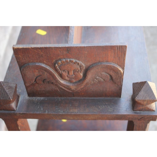 538 - A 19th century dark oak three-tier book stand with carved angel head decoration, 17