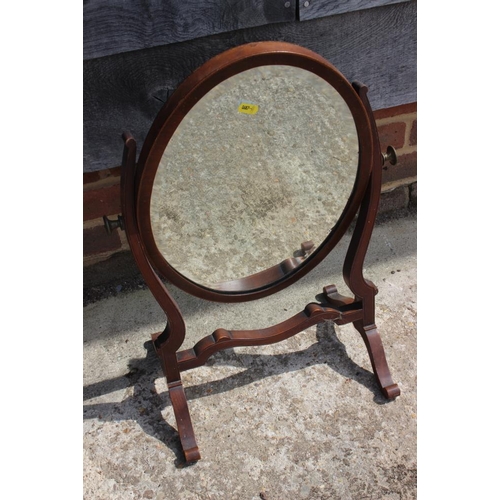 606 - A mahogany oval shaped swing frame mirror with bevelled plate, 15