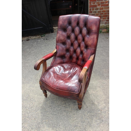 616 - A button back armchair, upholstered in a nailed crimson leather, on turned supports