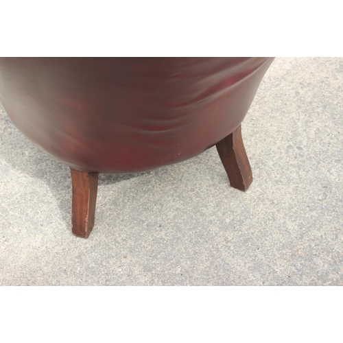 616 - A button back armchair, upholstered in a nailed crimson leather, on turned supports