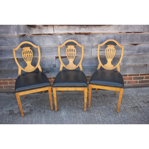 630 - * A set of three satin birch standard dining chairs of Sheraton design with pierced shield-shaped ba... 