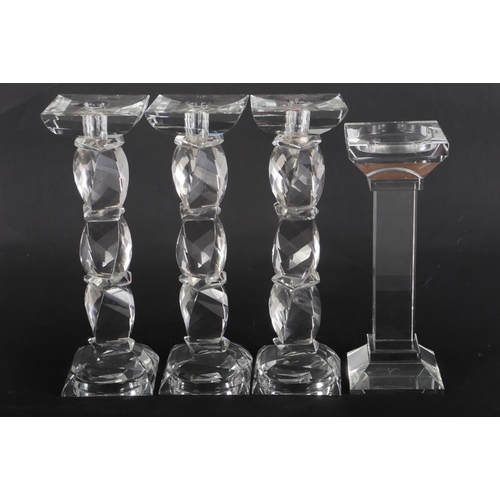 111 - A set of three Kenneth Turner glass candlesticks, on facet cut stems, another plain square-section c... 