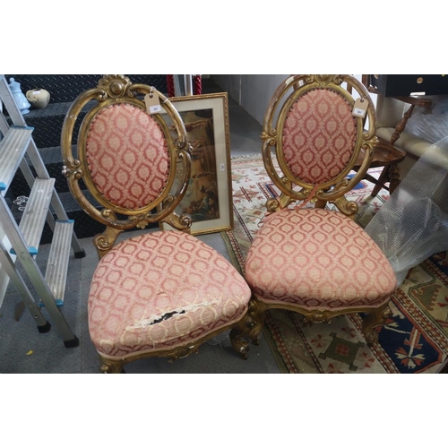 553 - A pair of French giltwood framed salon chairs with oval backs, upholstered in a pink brocade, on cab... 