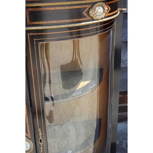 506 - A late Victorian ebonised break bowfront credenza, the centre door inset Sevres enamelled panel with... 