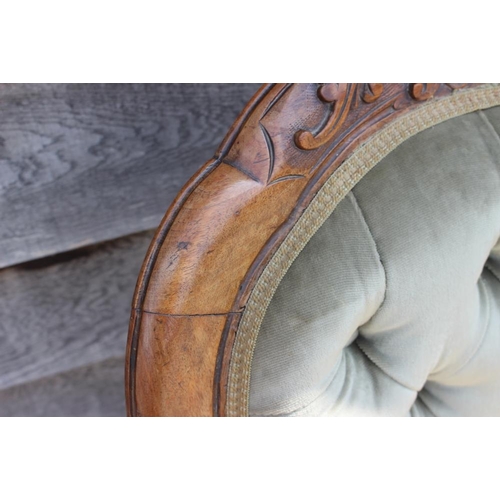 518 - A late 19th century carved walnut showframe low seat nursing chair, upholstered in a green velour, o... 