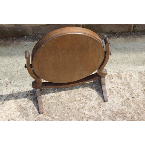 560 - A mahogany oval swing frame toilet mirror, on skeleton stand, 10 1/2