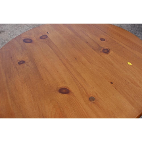 684 - A waxed pine circular dining table, on turned supports, 40