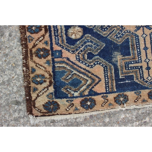 697 - A Caucasian tribal rug with one medallion on a blue ground and multi-bordered in shades of pink, 48