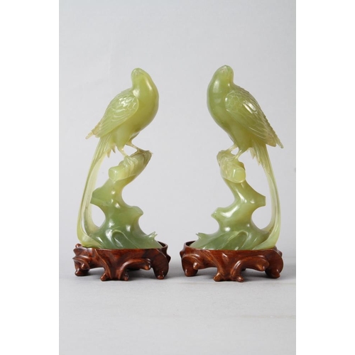 124 - A pair of Chinese carved jade model birds, on hardwood stands, 7 1/2