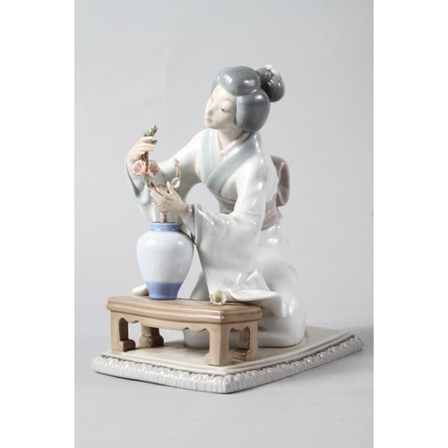 25 - A Lladro figure of a Geisha arranging flowers in a vase, 7 3/4