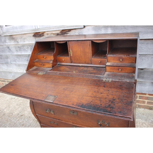 534 - An early 19th century Continental oak bombe-shape fall front bureau, the upper section fitted drawer... 