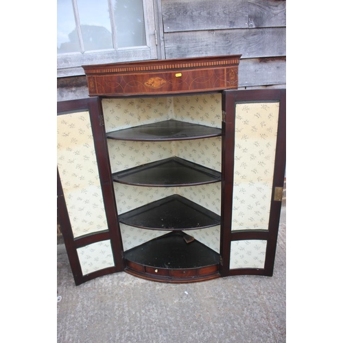 536 - A Georgian mahogany and line inlaid with shell paterae bowfront corner cupboard, interior fitted two... 