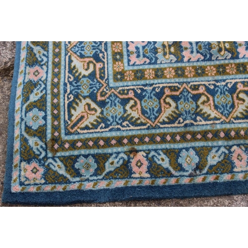 704 - A Caucasian rug of traditional design with two central medallions on a blue ground in shades of gree... 