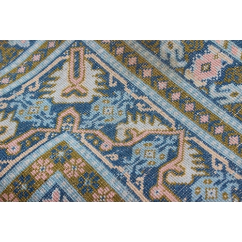 704 - A Caucasian rug of traditional design with two central medallions on a blue ground in shades of gree... 