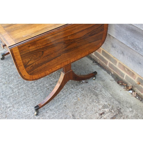 529 - A George IV rosewood and satinwood banded sofa table, fitted two drawers, on panel end splay support... 