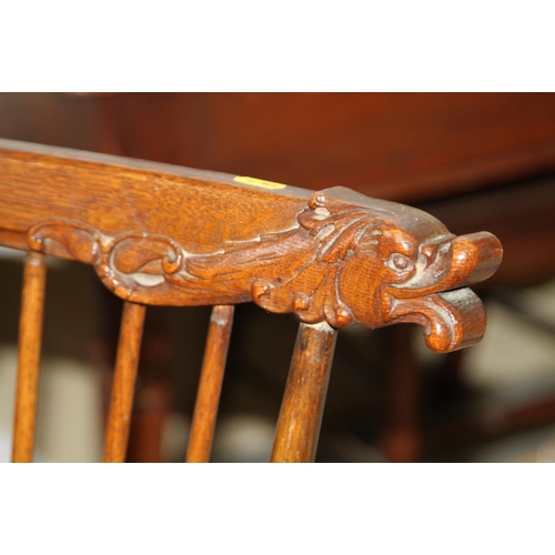 520 - A late 19th century carved oak spindle back elbow chair with dolphin head top rail and panel seat