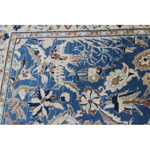 699 - A Persian Nain rug, finely woven with all-over floral design on a blue ground and multi-bordered in ... 