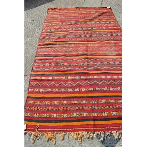 741 - A Moroccan kelim type rug with geometric decoration in shades of orange, red and black, 107