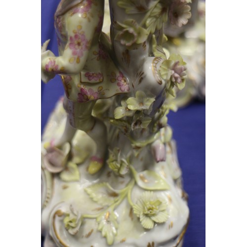 29 - A pair of late 19th century Dresden porcelain candlesticks with figures, on scroll bases, 9 1/4