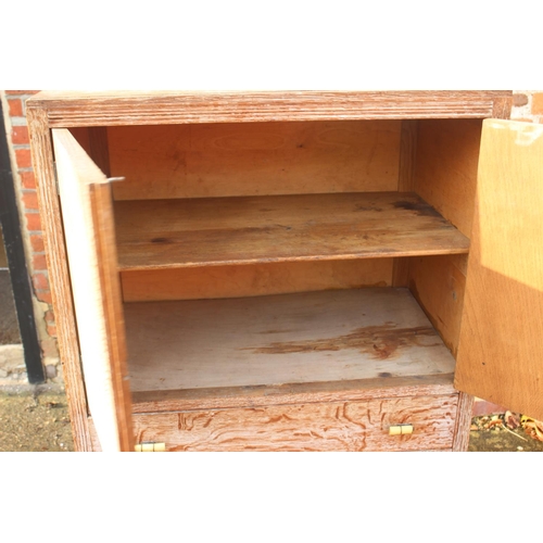 566 - A 1930s limed oak linen cupboard enclosed two doors over three drawers, 30