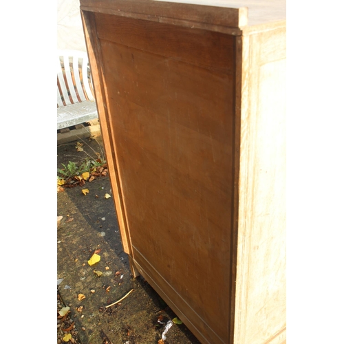 566 - A 1930s limed oak linen cupboard enclosed two doors over three drawers, 30