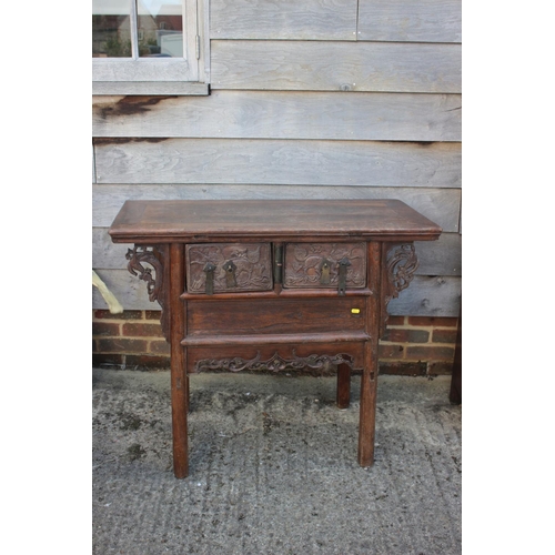 610 - A Chinese carved elm side table, fitted two drawers, on turned supports, 39