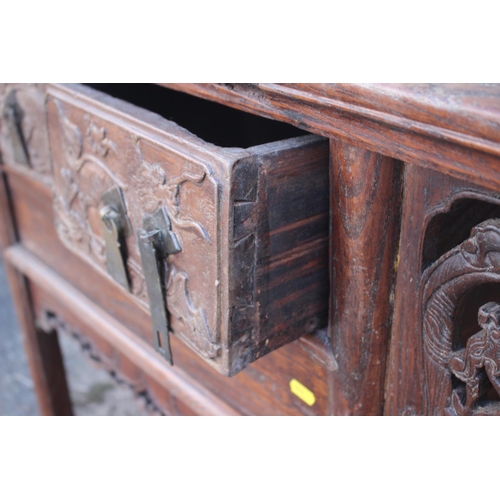 610 - A Chinese carved elm side table, fitted two drawers, on turned supports, 39