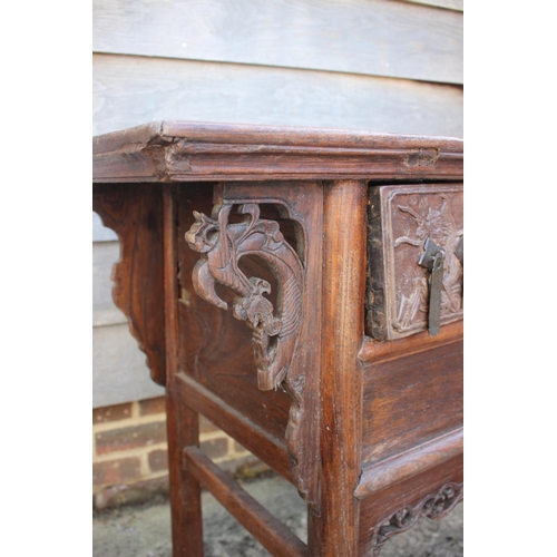 610 - A Chinese carved elm side table, fitted two drawers, on turned supports, 39