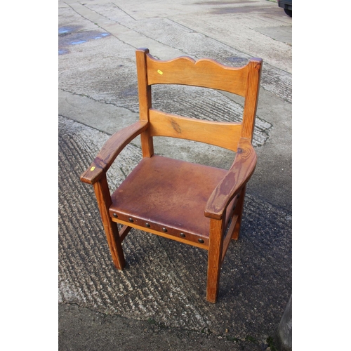 663 - A pine elbow chair with studded leather seat, on stretchered supports