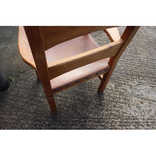 663 - A pine elbow chair with studded leather seat, on stretchered supports