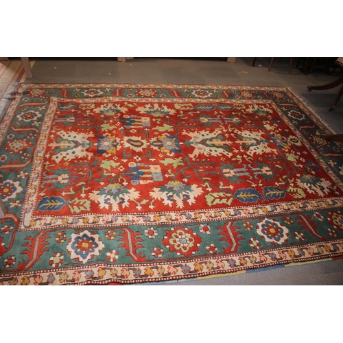 668 - A Kazak style rug with all-over geometric design on a red ground with floral borders, in shades of r... 