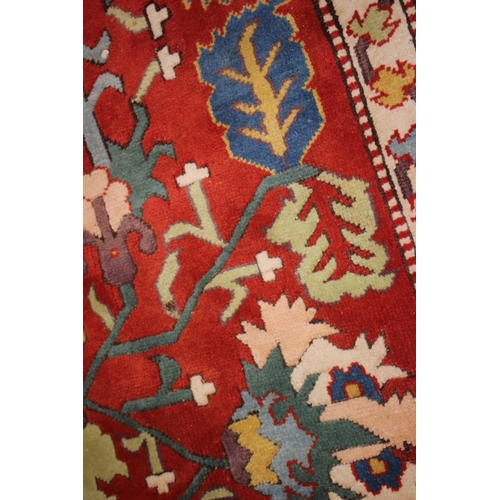 668 - A Kazak style rug with all-over geometric design on a red ground with floral borders, in shades of r... 