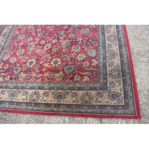 669 - A Persian style machine woven rug with floral designs on a red ground in shades of natural, blue and... 