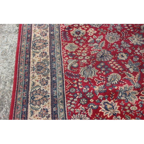 669 - A Persian style machine woven rug with floral designs on a red ground in shades of natural, blue and... 