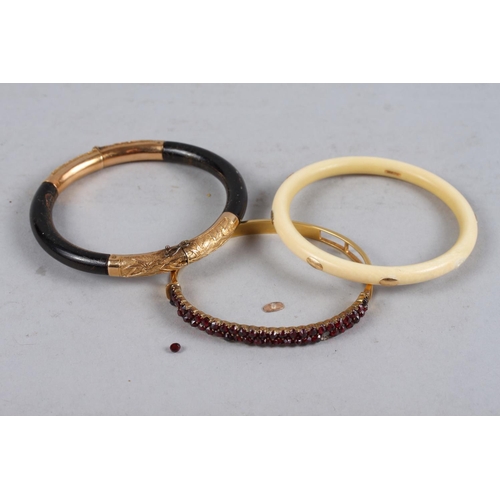 314 - A Chinese yellow metal and ebonised hinged bangle, an ivory bangle with yellow metal mounts, and a y... 