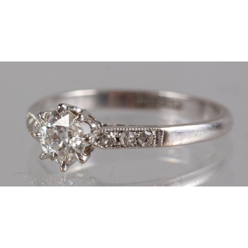 323 - A platinum and diamond dress ring, the central stone flanked three small diamonds to each shoulder, ... 