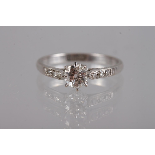 323 - A platinum and diamond dress ring, the central stone flanked three small diamonds to each shoulder, ... 