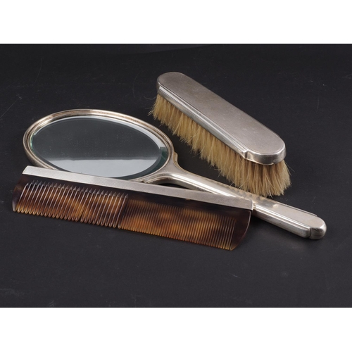 288 - An engine turned silver backed toilet mirror, and a companion brush and comb