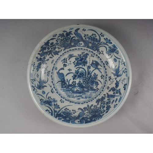 30 - An 18th century Dutch Delft blue and white glazed charger with bird, plant and flower decoration, 13... 