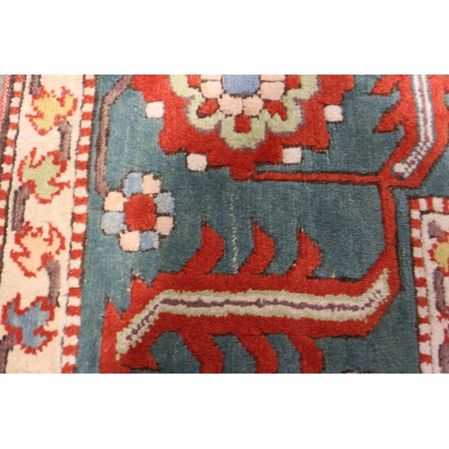 668 - A Kazak style rug with all-over geometric design on a red ground with floral borders, in shades of r... 