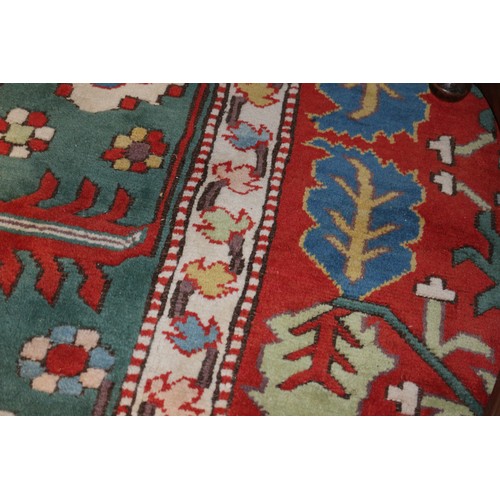 668 - A Kazak style rug with all-over geometric design on a red ground with floral borders, in shades of r... 