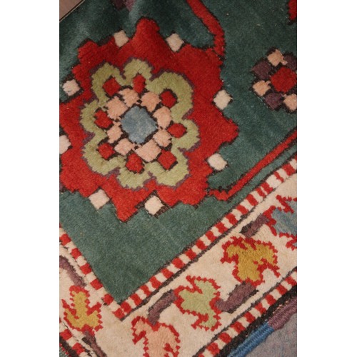 668 - A Kazak style rug with all-over geometric design on a red ground with floral borders, in shades of r... 