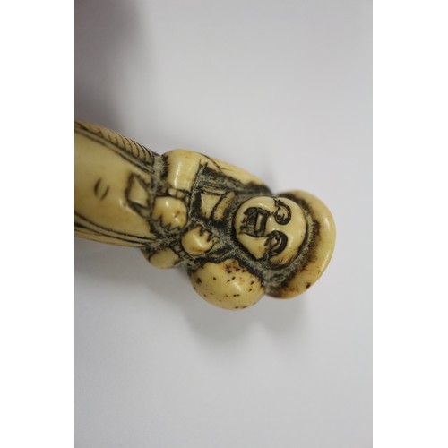 117 - A Japanese carved antler netsuke, formed as a Dutchman holding a ham hock, 2 1/4