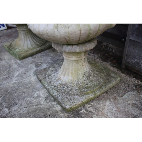 753 - A pair of cast stone urns with classical decoration, on square bases, 42