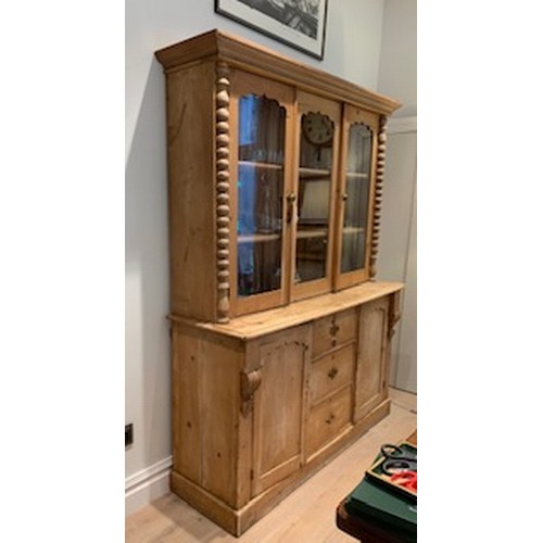 744 - A stripped pine bookcase, the upper section enclosed three shaped panel glazed doors over three cent... 